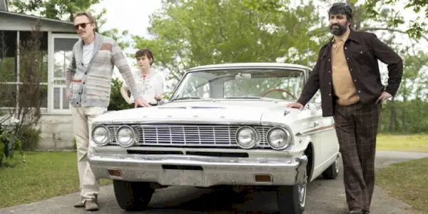 Two men and a woman standing outside a car in Uncle Frank