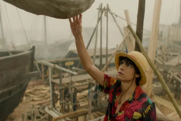 One Piece still showing Luffy reaching up to touch a boulder