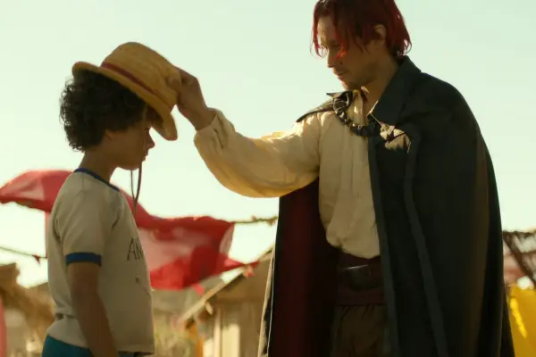 Colton Osorio as Young Luffy having a hat put on his head by Peter Gadiot as Shanks in Netflix