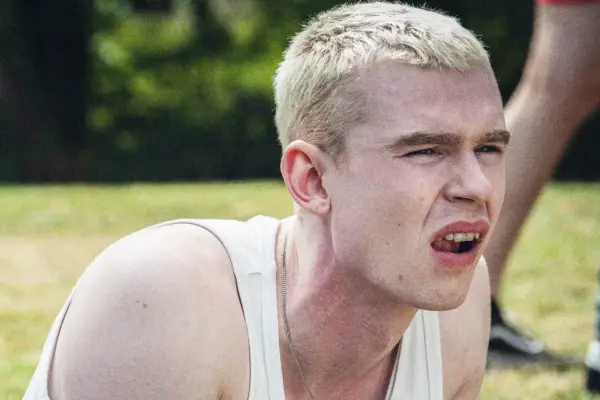 Cam wearing a white vest, lying on the grass in the park