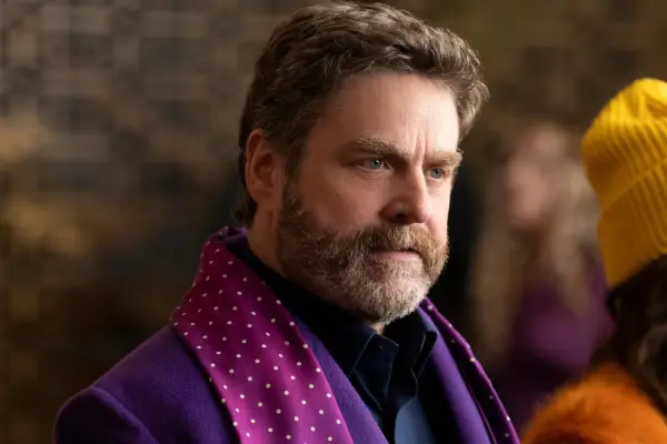 Zach Galifianakis as himself in Only Murders in the Building season 4 wearing a purple shirt and matching scarf.