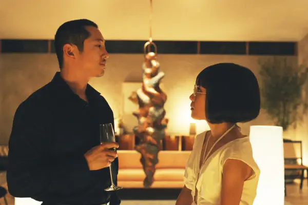 Danny and Amy standing opposite one another at a gathering, the atmosphere is tense