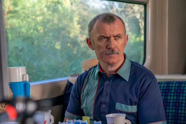 Tommy Tiernan wearing a blue shirt, scowling at something.