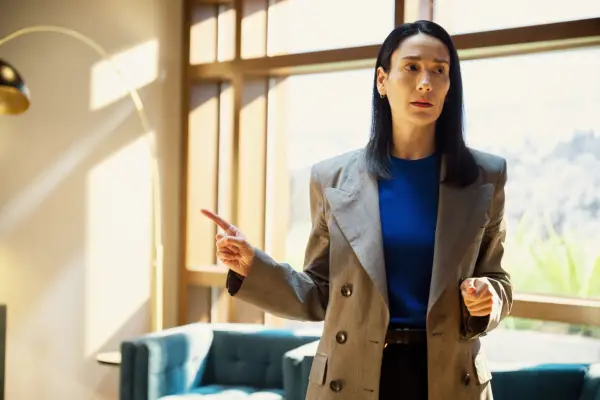 Anna stood in an office with her right arm raised and finger outstretched