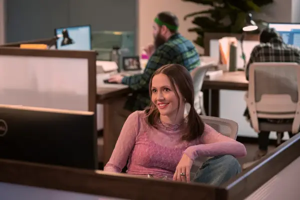 Georgia sits at her office cubicle in a relaxed pose, smiling