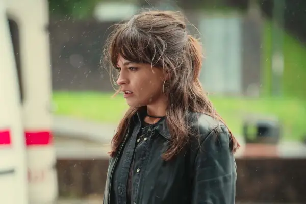 Emma Mackey plays Maeve Wiley in Sex Education season 4 wearing a leather jacket, looking concerned