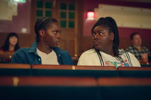 Kedar Williams-Stirling as Jackosn Marchetti and Chinenye Ezeudu as Vivian Odusanya in Sex Education season 4 sitting together, looking at each other