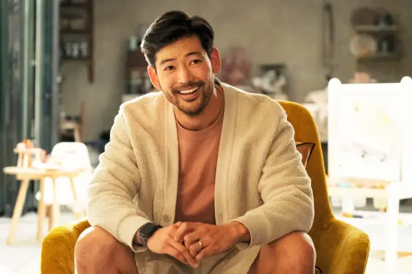 george sat in an arm chair, leaning forward, with a smile on his face