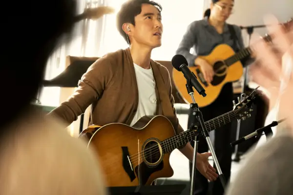 Edwin stood on stage with his band, wearing his guitar and holding his mic