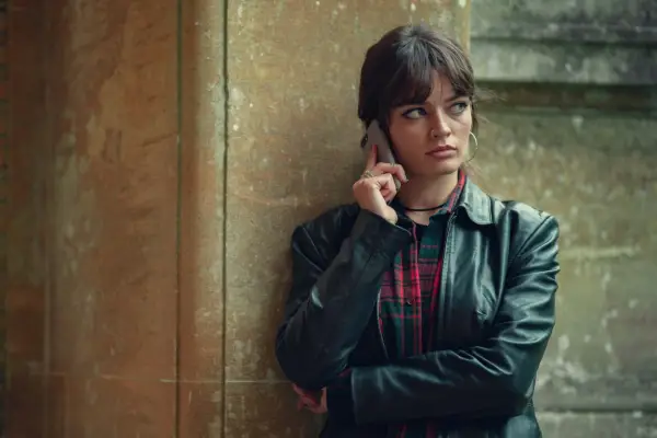 Emma Mackey stars in Sex Education season 4 as Maeve Wiley holding a phone to her ear