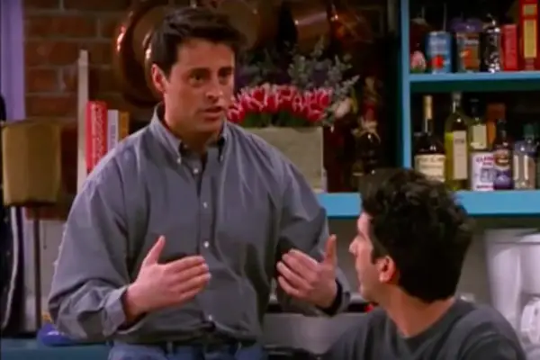 Joey talking with his hands outwards, as Ross watches on