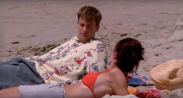 Chandler and Monica from Friends lying on the beach