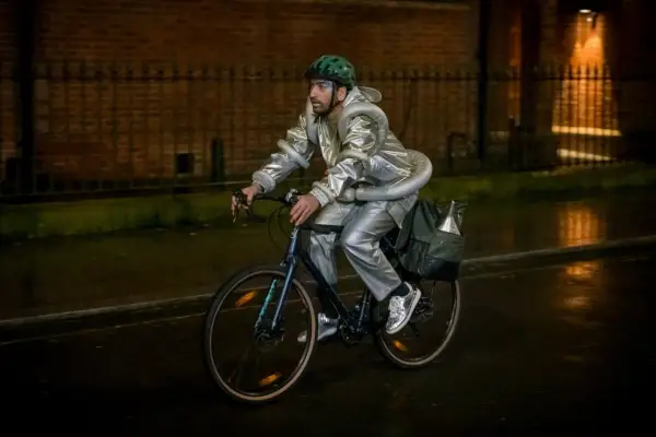 Nabhaan Rizwan as Noa in Film Club, wearing a silver costume and bicycle helmet, and riding a bike.