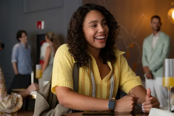 Emma Ferreira as Ness in Neon wearing a yellow jumper, smiling