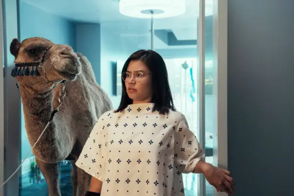 Maya in a hospital wearing a gown with a camel stood behind her