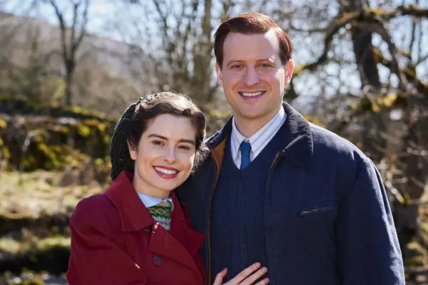 Nicholas Ralph and Rachel Shenton in All Creatures Great and Small, standing together, smiling into camera