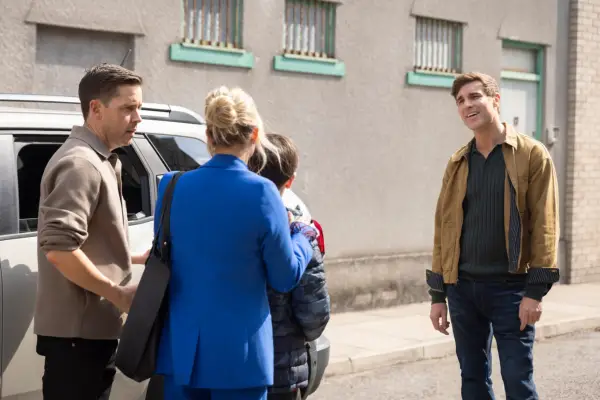 Theo smiling at Sarah and Harry as Todd looks on in Coronation Street