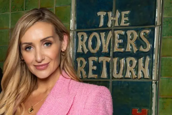 Catherine Tyldesley in a pink blazer in front of the Rovers Return sign as Eva Driscoll in Coronation Street.