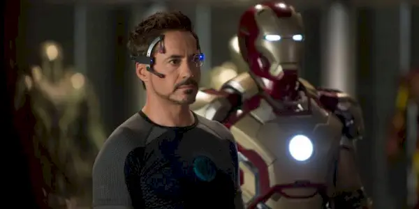 Tony Stark standing next to his suit of armor in Iron Man 3.