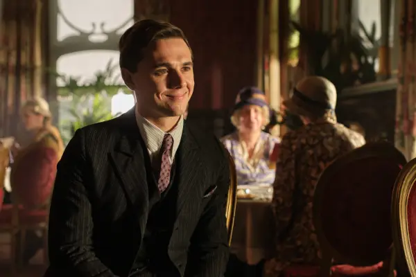 Calam Lynch as young Archie in Archie wearing a suit at a table and smiling.