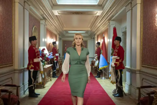 Kate Winslet walks down a palace corridor lined with guards as The Chancellor in The Regime.