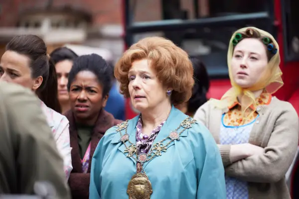 Violet Buckle (ANNABELLE APSION), wearing her mayor medal, standing in a crowd