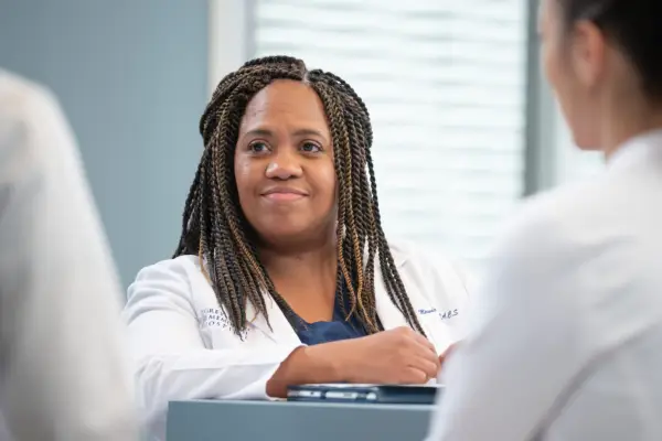 Chandra Wilson smiles as Dr Miranda Bailey in a white doctor coat in Grey