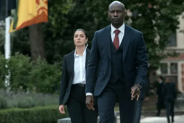 David Gyasi as Austin Dennison in The Diplomat, wearing a three-piece suit and walking outside.