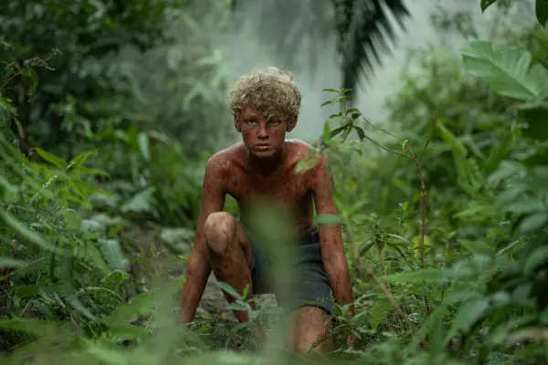 Lox Pratt as Jack in Lord of the Flies, shirtless and in the jungle.