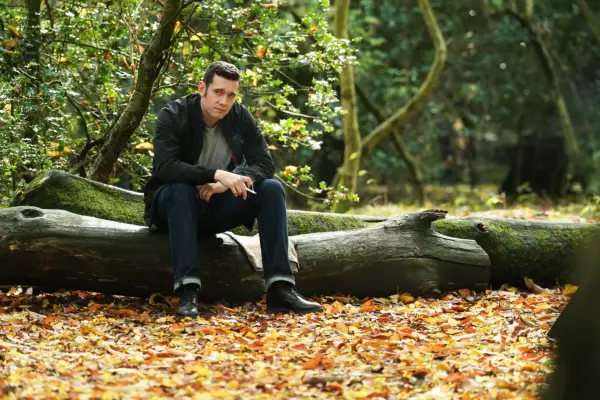 Will sat on a fallen tree trunk in a forest