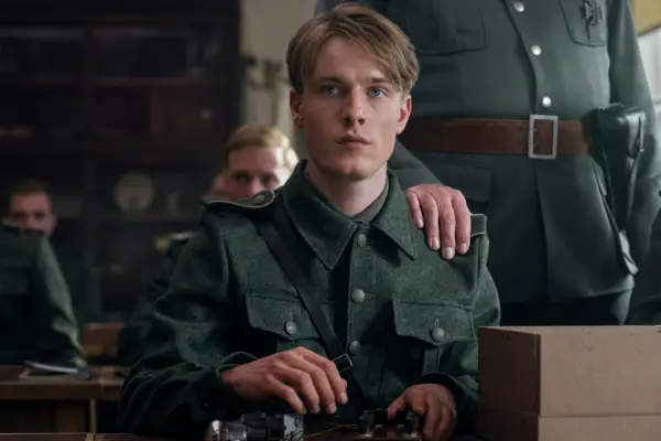 Louis Hofmann as Werner Pfennig in All the Light We Cannot See wearing a military outfit, as a man puts a hand on his shoulder