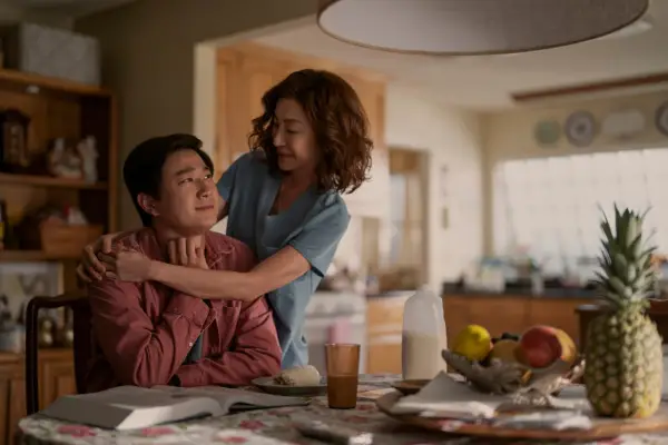 Sam Song Li as Bruce Sun and Michelle Yeoh as Mama Sun in The Brothers Sun hugging each other at a dinner table