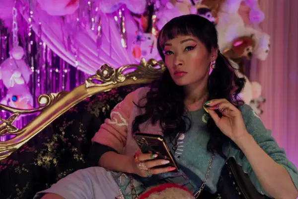 Alice Hewkin as June in The Brothers Sun sitting on a chaise longue on her phone