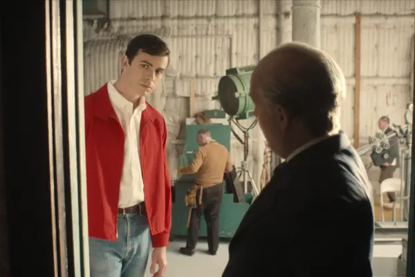 Joey Pollari as Anthony Perkins, Tom Hollander as Alfred Hitchcock in Monster: The Ed Gein Story on a film set and having a conversation.