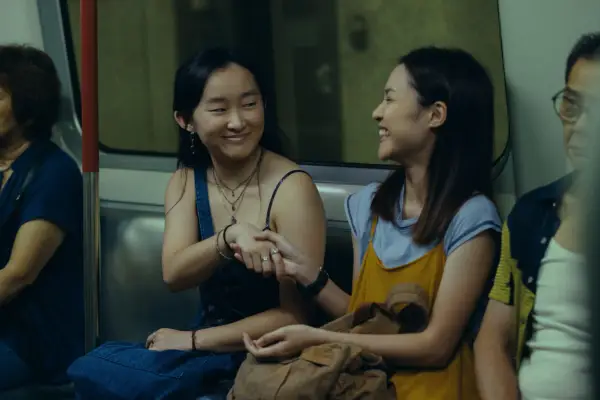 Ji-young Yoo as Mercy and Bonde Sham as Charly in Expats meeting and shaking hands on a train.