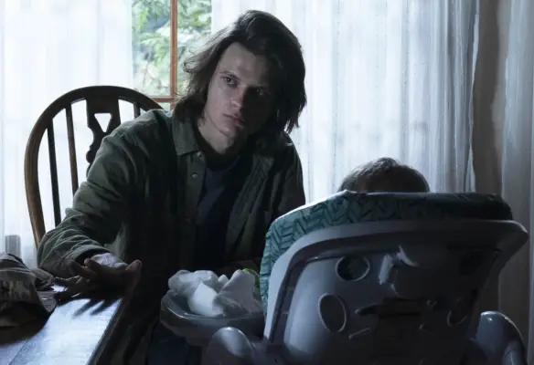 Charlie Tahan as Wyatt Langmore sitting with a baby in a carrier in Ozark