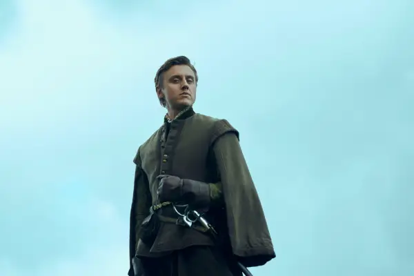 Jacob McCarthy as Kit Villiers in Mary & George standing outside and wearing a matching suit