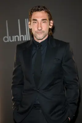 Samuel Blenkin as Charles in Mary & George sitting in a seat and wearing a blue suit.