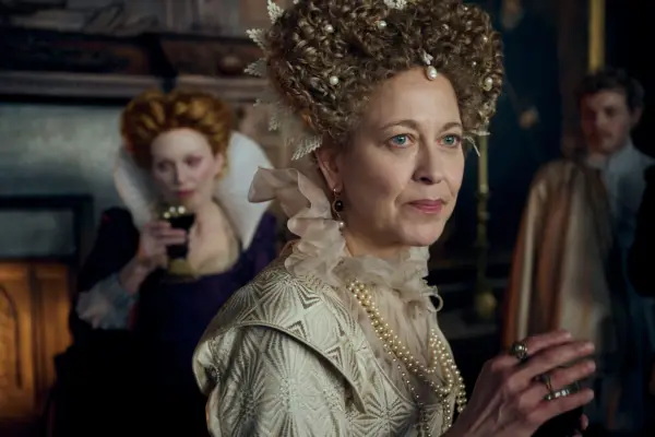 Nicola Walker and Julianne Moore standing in the middle of a room, dressed up with hair pinned up and not facing each other.