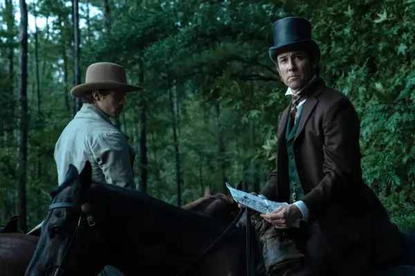 Tobias Menzies as Edwin Stanton and Brandon Flynn as Edwin Stanton Jr in Manhunt. They are both sat on horses and going through the woods