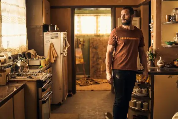 Jamie Dornan wearing a red t-shirt looking concerned