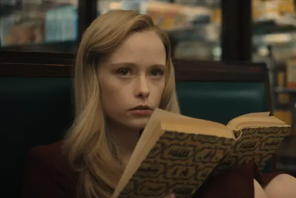 Suzanna Son as Adeline Watkins sat down with a book resting on her knees.