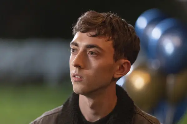 Joe Barber as Jordan standing on a street at night and looking surprised in Coma.