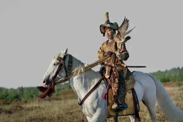 Hiroyuki Sanada as Yoshii Toranaga in Shōgun wearing regal gold dress and on a white horse in the middle of a field.