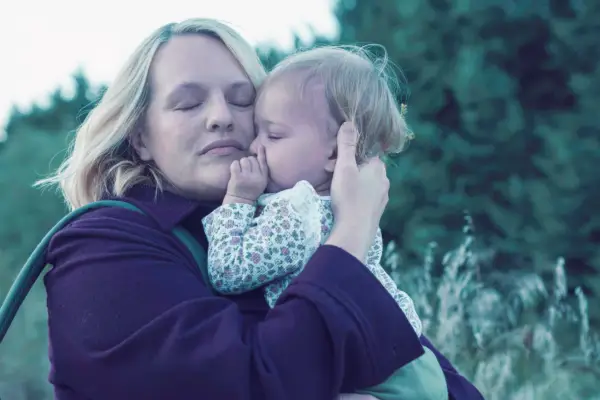 Elisabeth Moss plays June, holding a baby, her eyes are closed