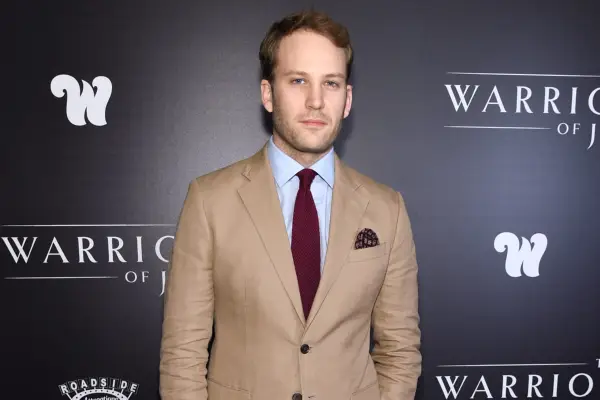 Ben Lamb wearing a beige suit with light blue shirt and red tie