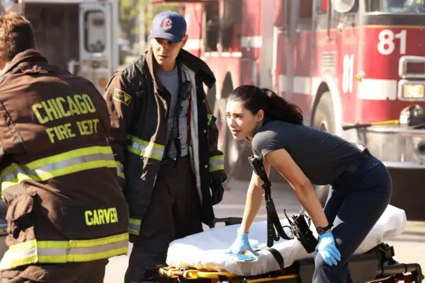 Hanako Greensmith as Violet Mikami in Chicago Fire, leaning over a stretcher, with a fire engine in the background