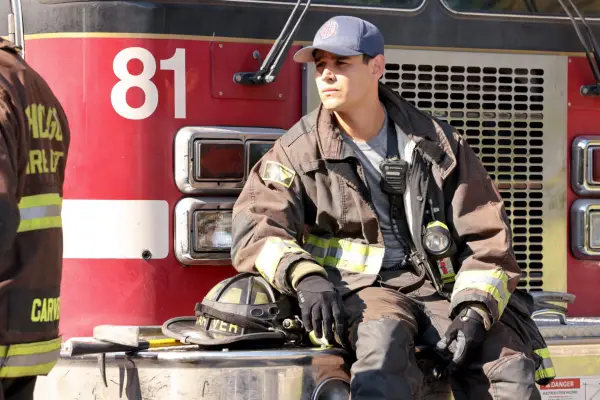Alberto Rosende as Blake Gallo in Chicago Fire, wearing his uniform and sat next to a fire engine