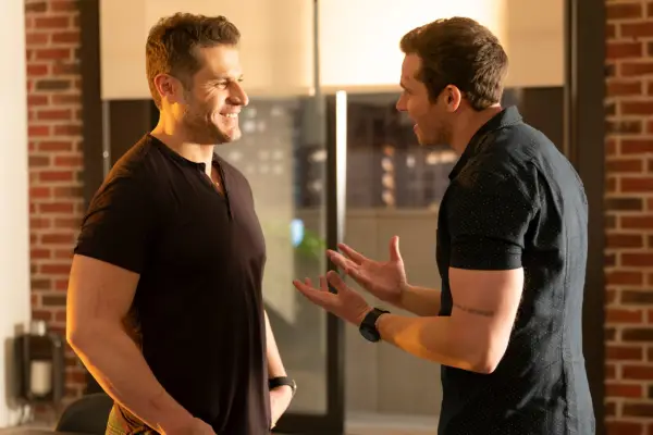 Lou Ferrigno Jr and Oliver Stark talking closely and smiling at each other.