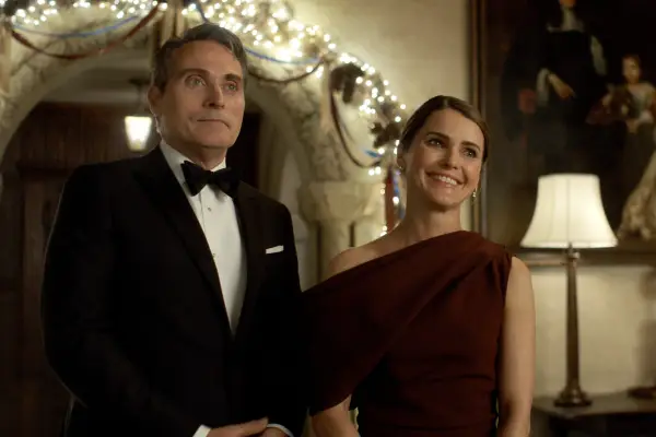 Rufus Sewell as Hal Wyler and Keri Russell as Kate Wyler in The Diplomat. They are stood together at an event, wearing formal clothes and smiling.
